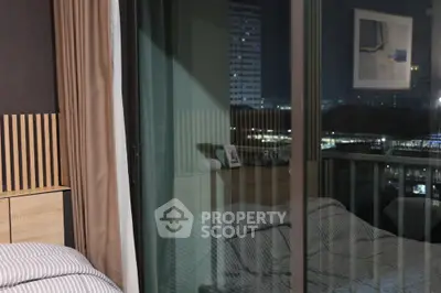 Modern bedroom with city view through glass balcony door at night