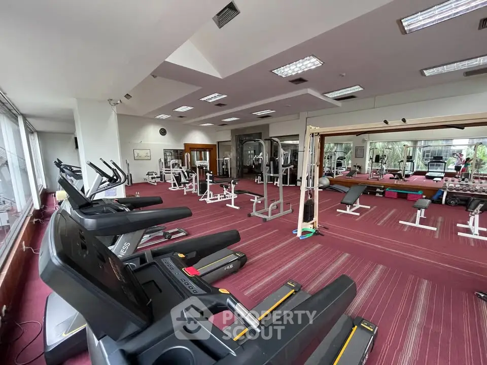Spacious gym with modern equipment and large mirrors in a residential building.