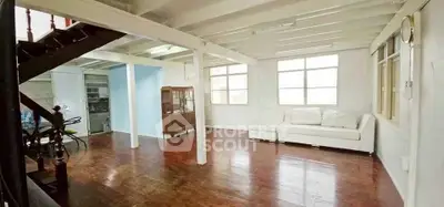 Spacious living room with wooden floors and natural light, perfect for relaxation and entertaining.