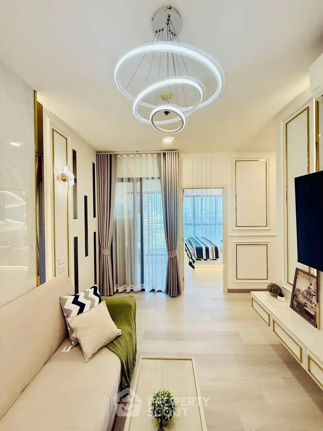 Modern living room with elegant lighting and view into a stylish bedroom, featuring contemporary decor and cozy ambiance.