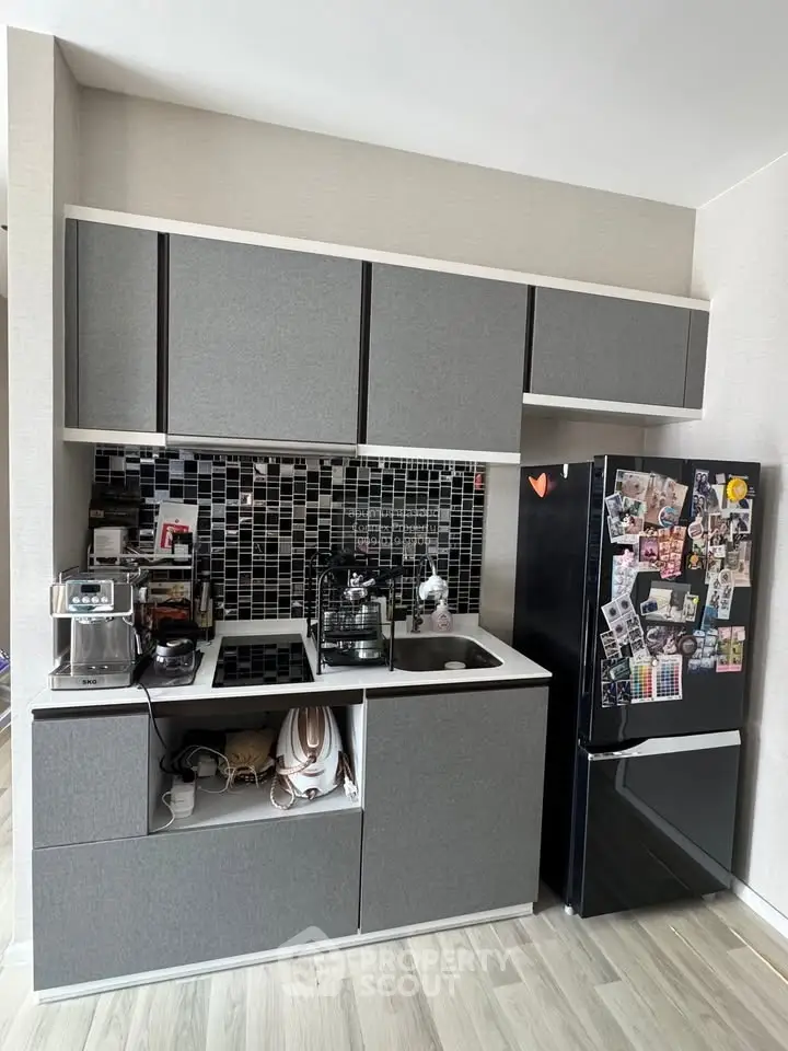 Modern kitchen with sleek cabinets and black fridge, featuring a stylish backsplash.