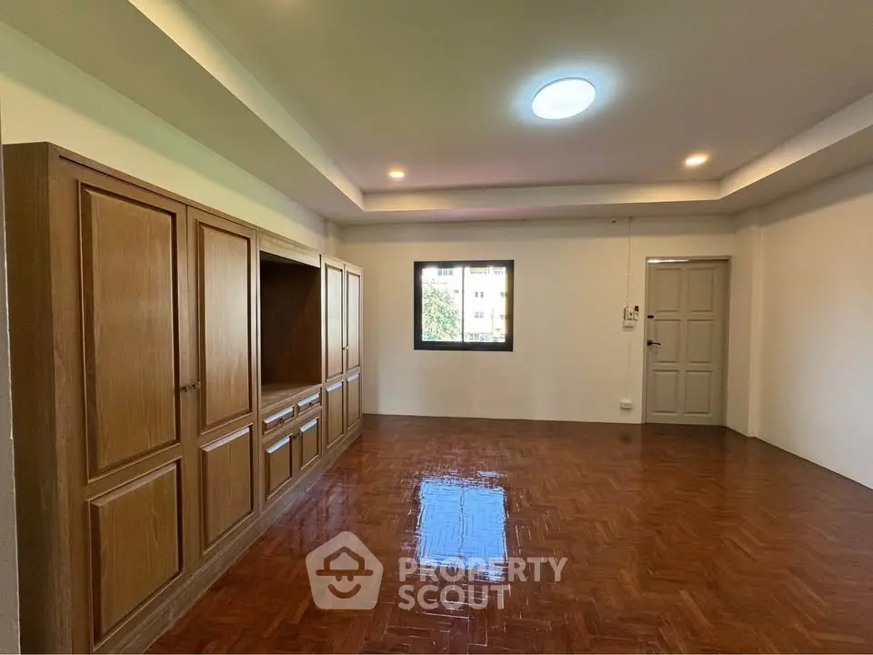 Spacious living room with wooden flooring and built-in cabinets, perfect for modern living.
