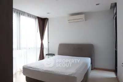 Bright and cozy bedroom with large window and modern air conditioning unit.