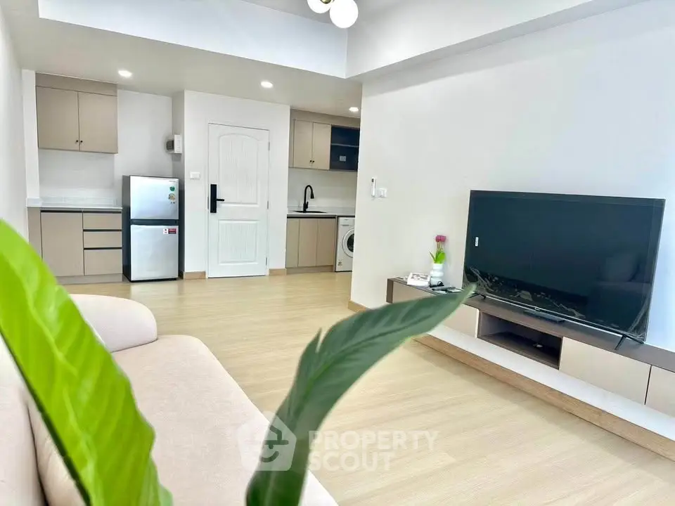 Modern living room with open kitchen, featuring sleek appliances and stylish decor.