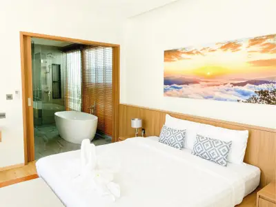 Luxurious bedroom with ensuite bathroom featuring a freestanding bathtub and scenic artwork.