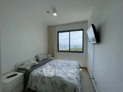 Modern bedroom with city view and wall-mounted TV in a high-rise apartment.
