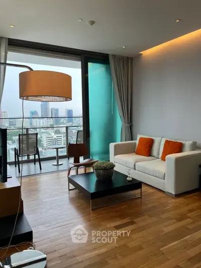 Modern living room with city view, stylish furniture, and large windows in a high-rise apartment.