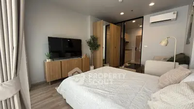 Modern bedroom with stylish decor, featuring a large TV, cozy bed, and elegant wooden furniture.