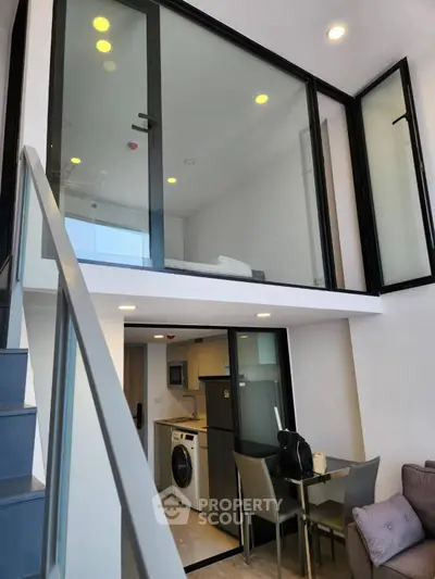 Modern duplex apartment with sleek design, featuring a compact kitchen and stylish dining area under a glass-walled loft.