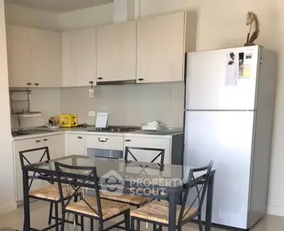 Modern kitchen with sleek cabinetry and dining area in a cozy apartment.
