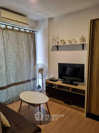 Cozy living room with modern decor, featuring a TV, air conditioning, and stylish furniture.