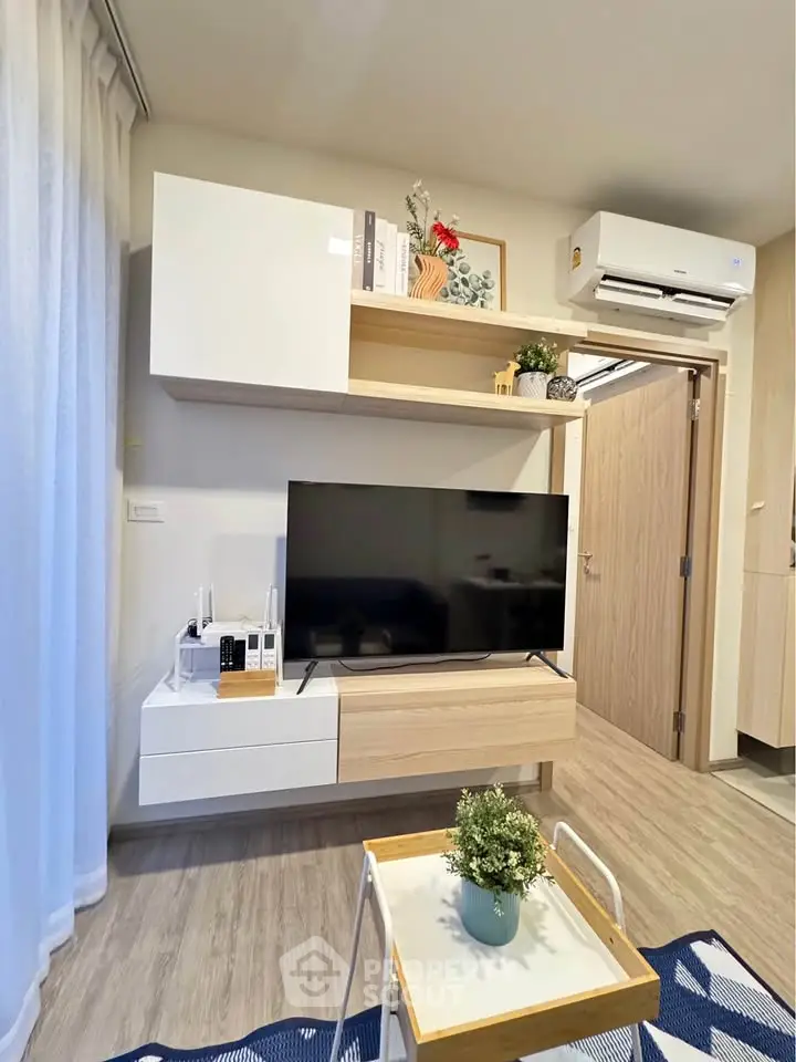 Modern living room with sleek TV unit and air conditioning, featuring stylish decor and natural light.