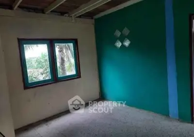 Spacious room with vibrant teal accent wall and large window offering natural light.