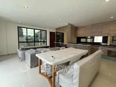 Spacious modern living room with open kitchen and large windows in a luxury apartment.