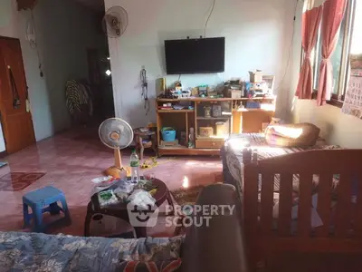 Cozy living room with TV, fan, and natural light from large windows.