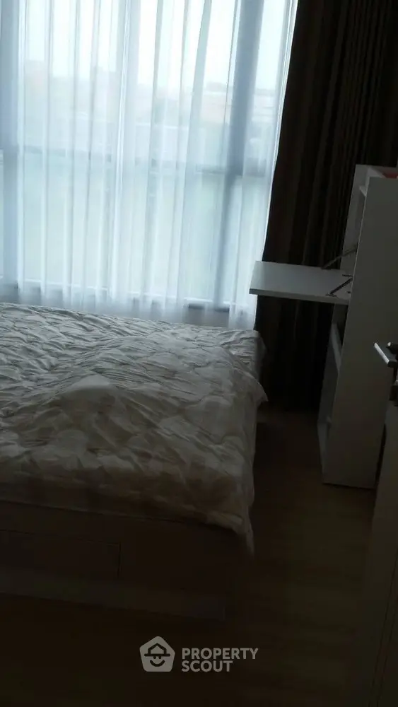 Cozy bedroom with large window and natural light, perfect for relaxation and comfort.
