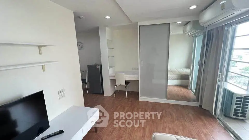 Modern apartment interior with wooden flooring, mirrored closet, and air conditioning.