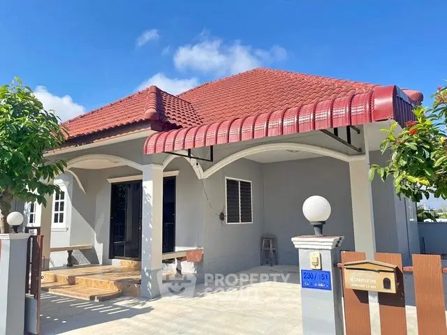 Charming single-story house with red-tiled roof and spacious front yard, perfect for family living.