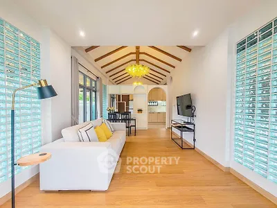 Spacious living room with modern decor and natural light, featuring a cozy sofa and stylish lighting.