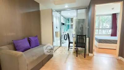 Modern apartment with open layout, featuring cozy living room, glass partition, and bedroom view.