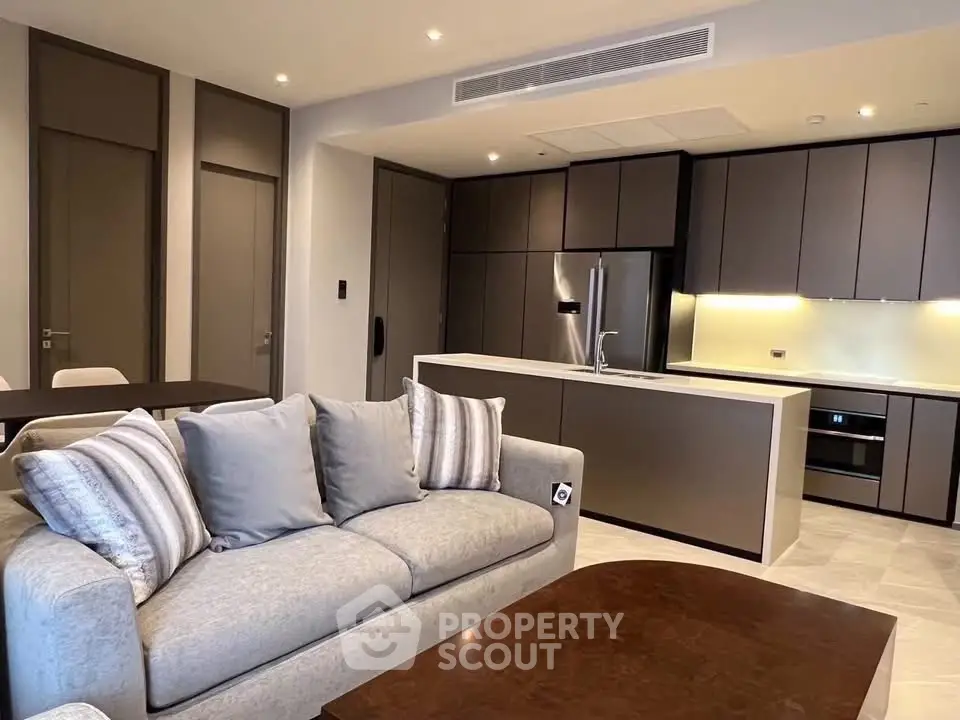 Modern open-layout living room with sleek kitchen design and stylish furniture.