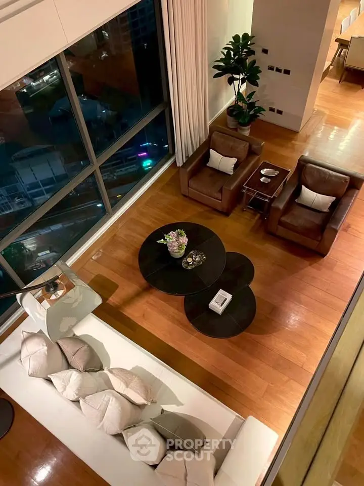 Luxurious living room with high ceiling and large windows offering stunning city views.