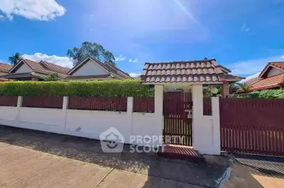Charming suburban house with tiled roof and lush greenery under clear blue sky.