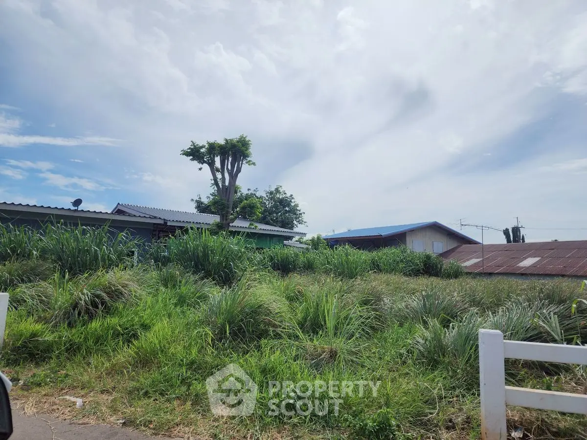 Charming rural property with lush greenery and rustic buildings under a bright sky.