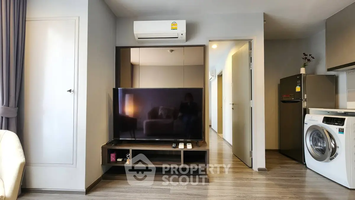 Modern living room with TV, air conditioning, and washing machine in a stylish apartment.
