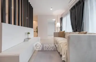 Elegant living room with modern decor and cozy seating area, featuring large windows and stylish curtains.