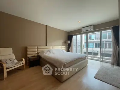 Spacious bedroom with modern decor and large windows for natural light.