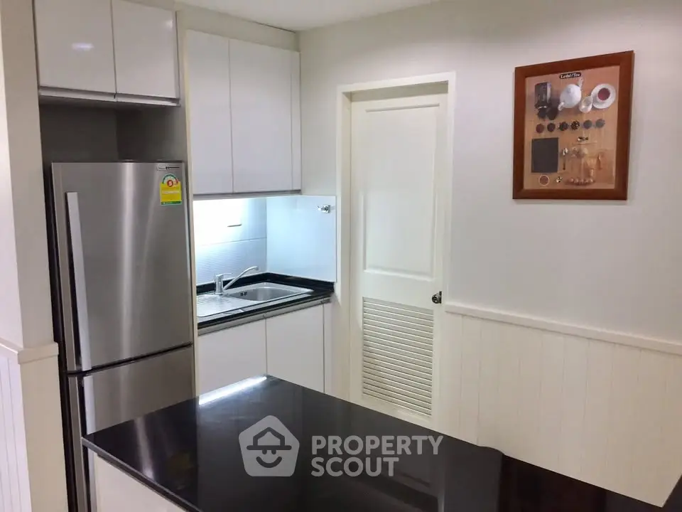 Modern kitchen with sleek cabinets and stainless steel fridge in a compact layout.