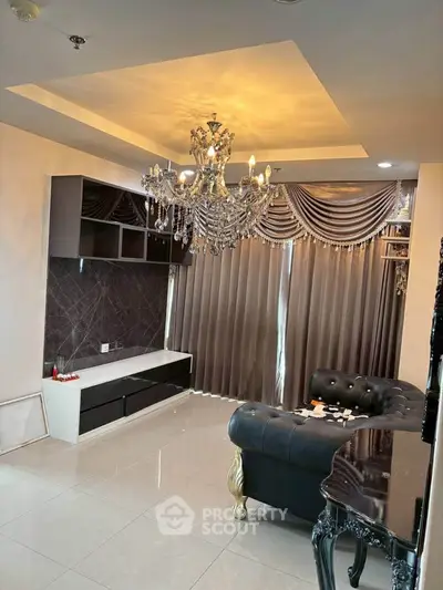 Luxurious living room with elegant chandelier and plush furnishings in a modern apartment.