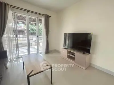 Modern living room with large TV and access to spacious balcony, perfect for relaxation.