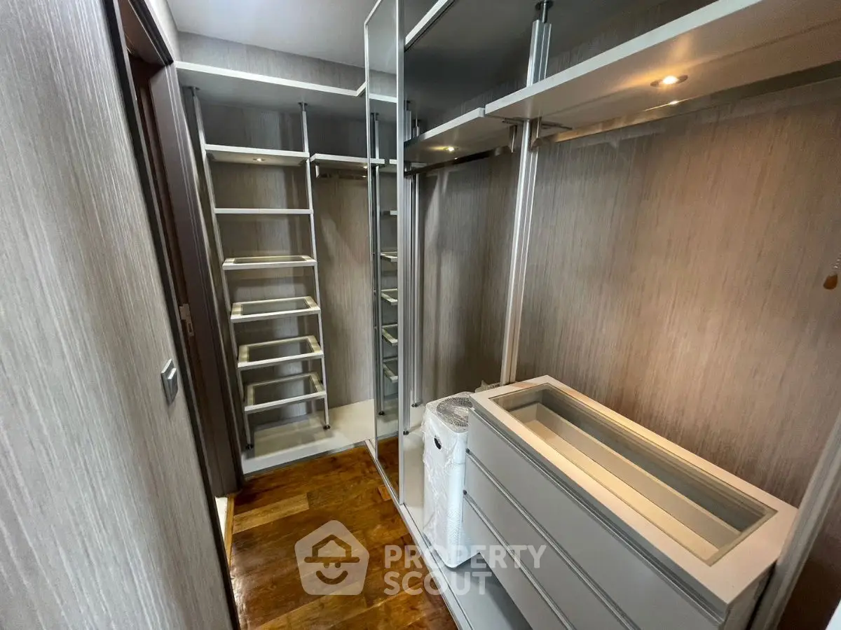 Spacious walk-in closet with modern shelving and wooden flooring.
