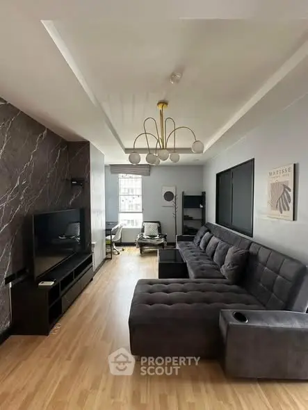 Modern living room with stylish decor and large sectional sofa, featuring elegant lighting and hardwood floors.