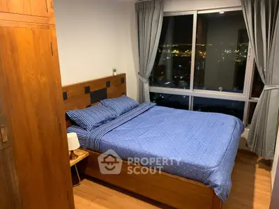 Cozy bedroom with city view, wooden furniture, and blue bedding