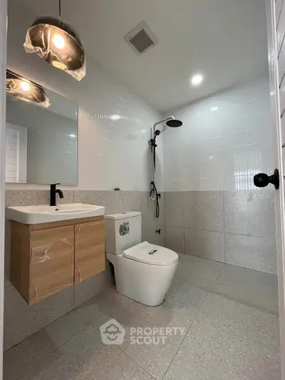 Modern bathroom with sleek fixtures and minimalist design, featuring a wall-mounted sink and rain shower.