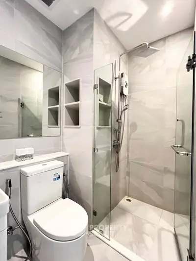 Modern bathroom with glass shower enclosure and sleek fixtures in a contemporary apartment.