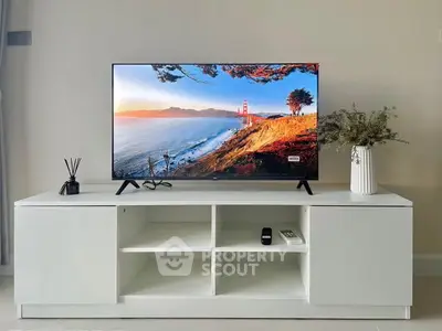 Modern living room with sleek TV stand and flat-screen TV displaying scenic view, enhancing home entertainment space.