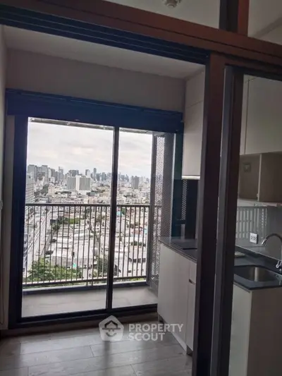 Modern apartment with city view from balcony and sleek kitchen design.