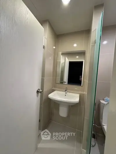 Modern bathroom with sleek design and neutral tones, featuring a wall-mounted sink and mirror.
