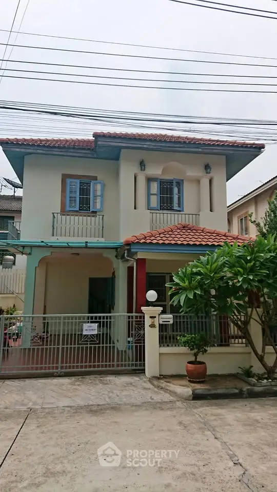 Charming two-story house with red-tiled roof and gated entrance in suburban neighborhood.