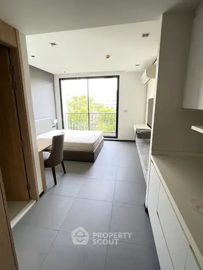 Modern studio apartment with large windows and minimalist design, featuring a compact kitchen and cozy living area.