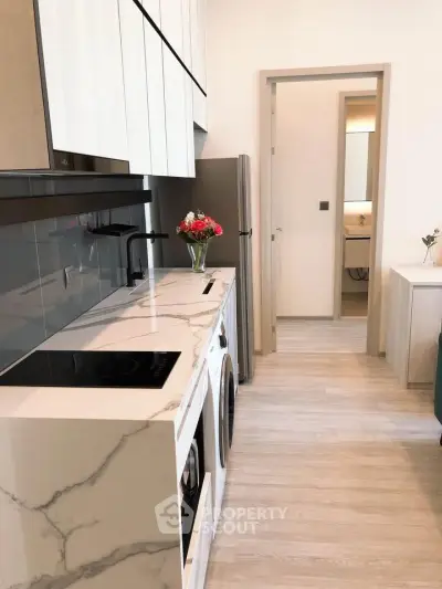Modern kitchen with sleek marble countertops and built-in appliances in a stylish apartment.