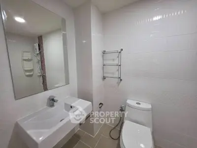 Modern bathroom with sleek fixtures and white tiles, featuring a large mirror and contemporary design.