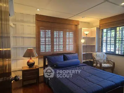 Cozy bedroom with blue bedding, wooden blinds, and warm lighting in a charming home.