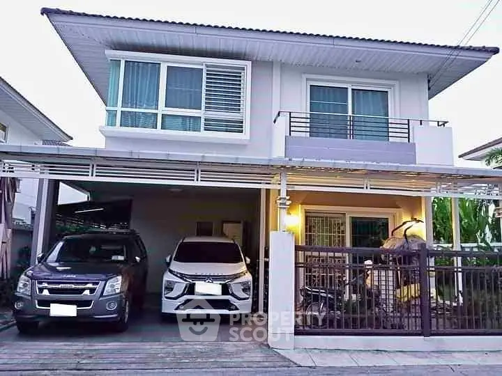 Modern two-story house with carport and balcony in suburban neighborhood.