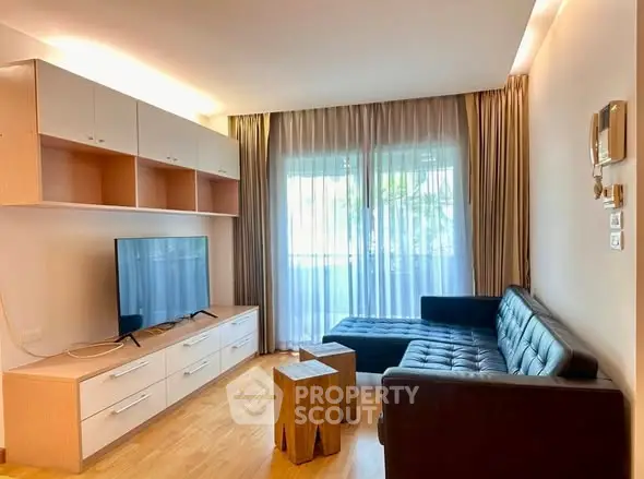 Modern living room with sleek furniture and natural light, featuring a stylish TV unit and comfortable seating.