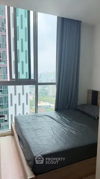 Modern bedroom with floor-to-ceiling windows offering stunning city views in a high-rise apartment.